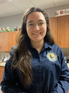 A young woman faces the camera and smiles in an office