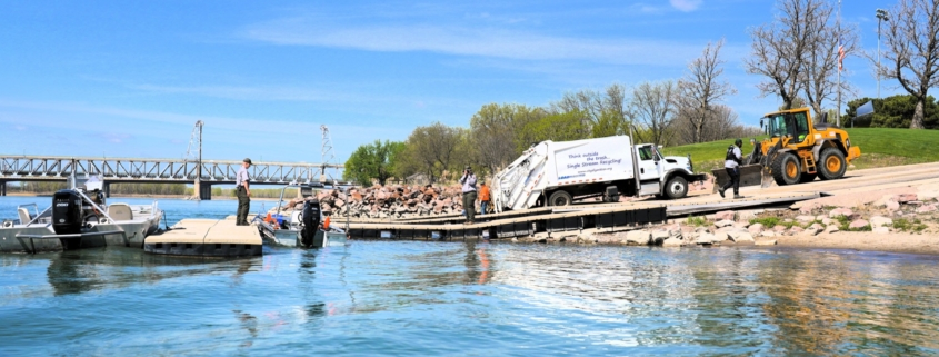 A view of a boat ramp with a multiple boats docked and a garbage truck parked on the ramp.