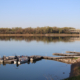Boats line a dock on water that is smooth as glass
