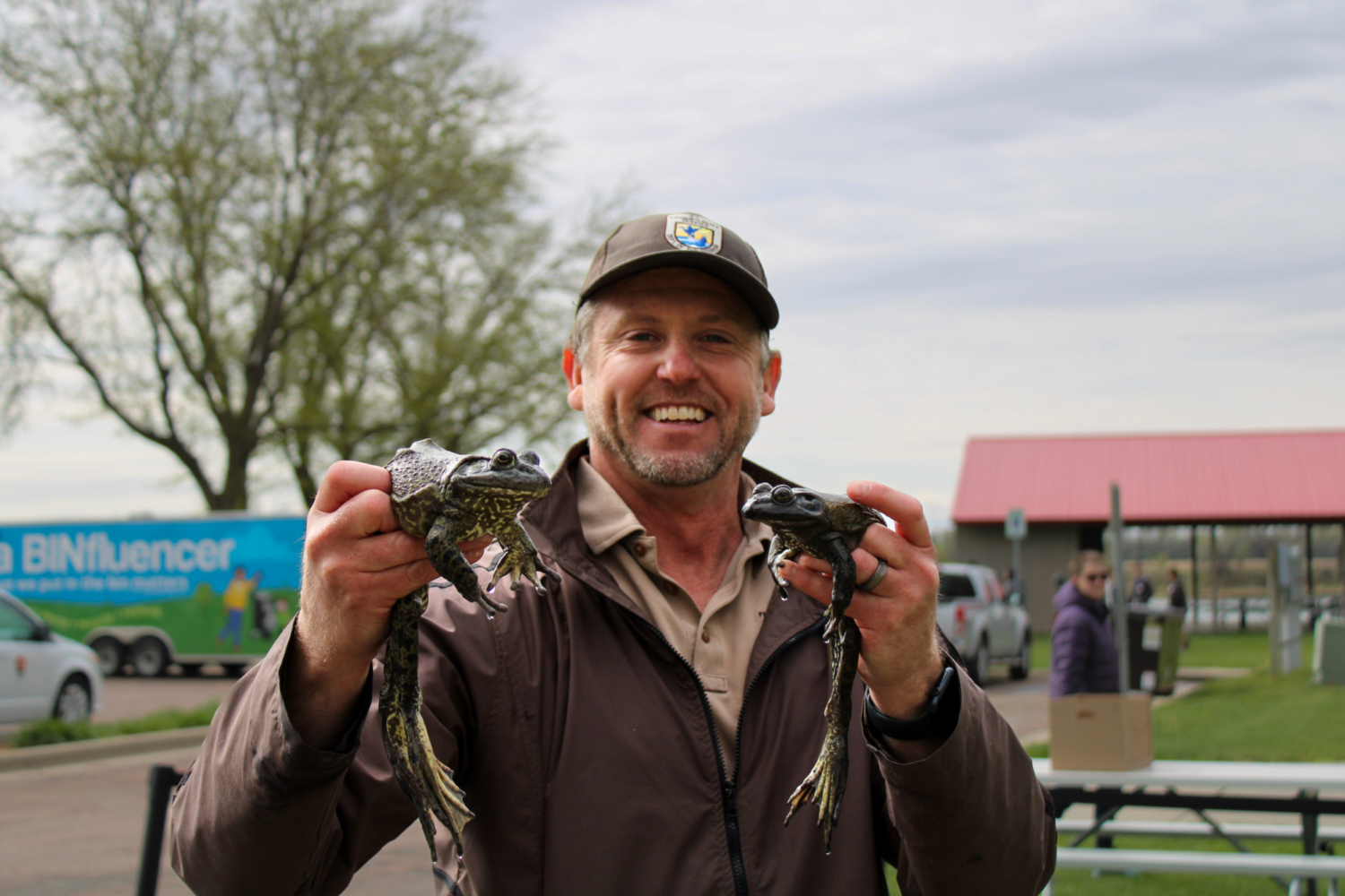 A man holds up two bullfrogs.