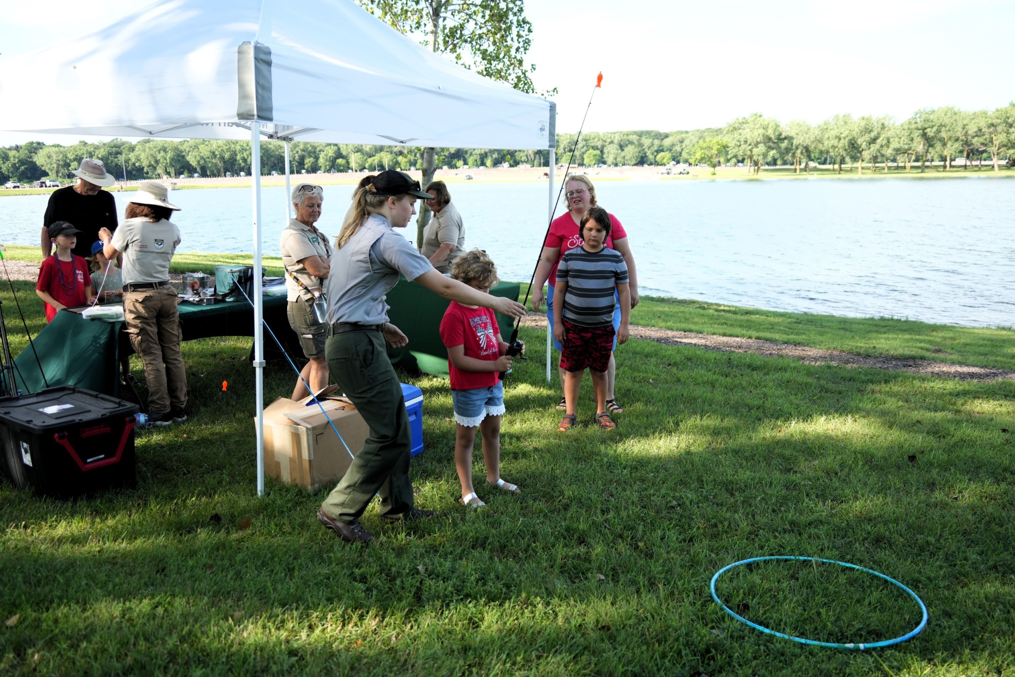 A group of people gathered under a tent next to a lake