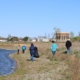 people walk spread out along a river shoreline