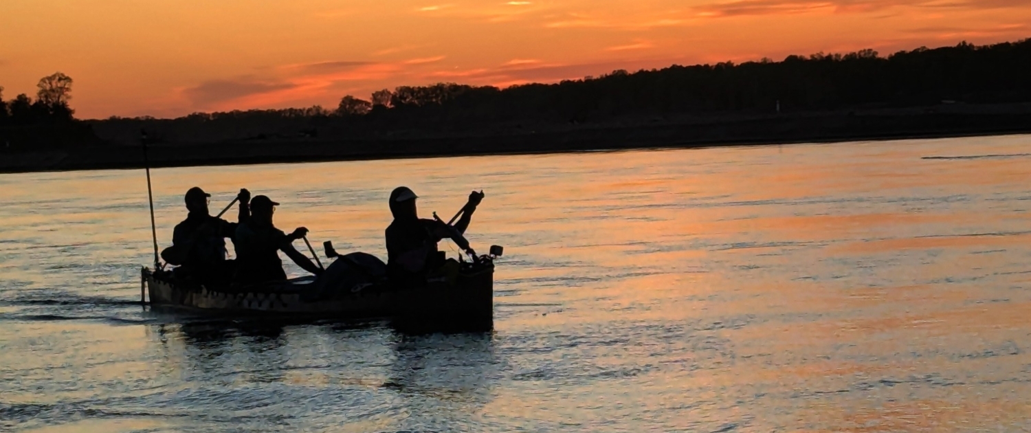Silhouette of paddlers in a canoe at sunset