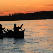 Silhouette of paddlers in a canoe at sunset