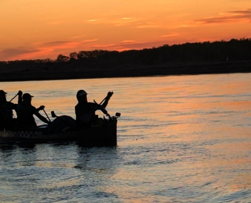 Silhouette of paddlers in a canoe at sunset