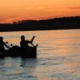 Silhouette of paddlers in a canoe at sunset