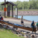 Four paddlers walk their canoe down a ramp