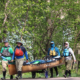Four people wearing lifejackets guide a canoe on portage wheels down a road