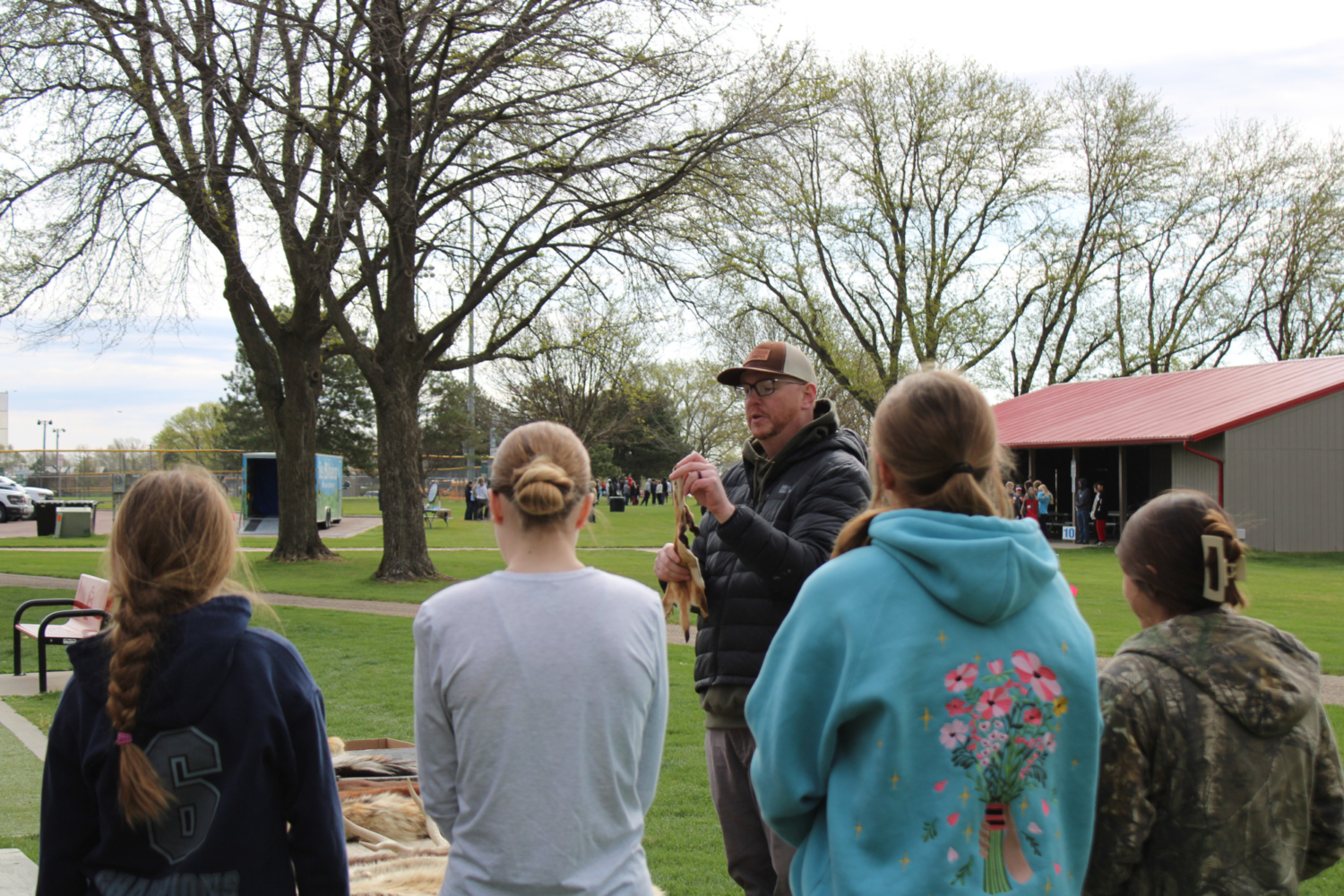 Students look on as a presenter talks about mammals and holds a pelt.