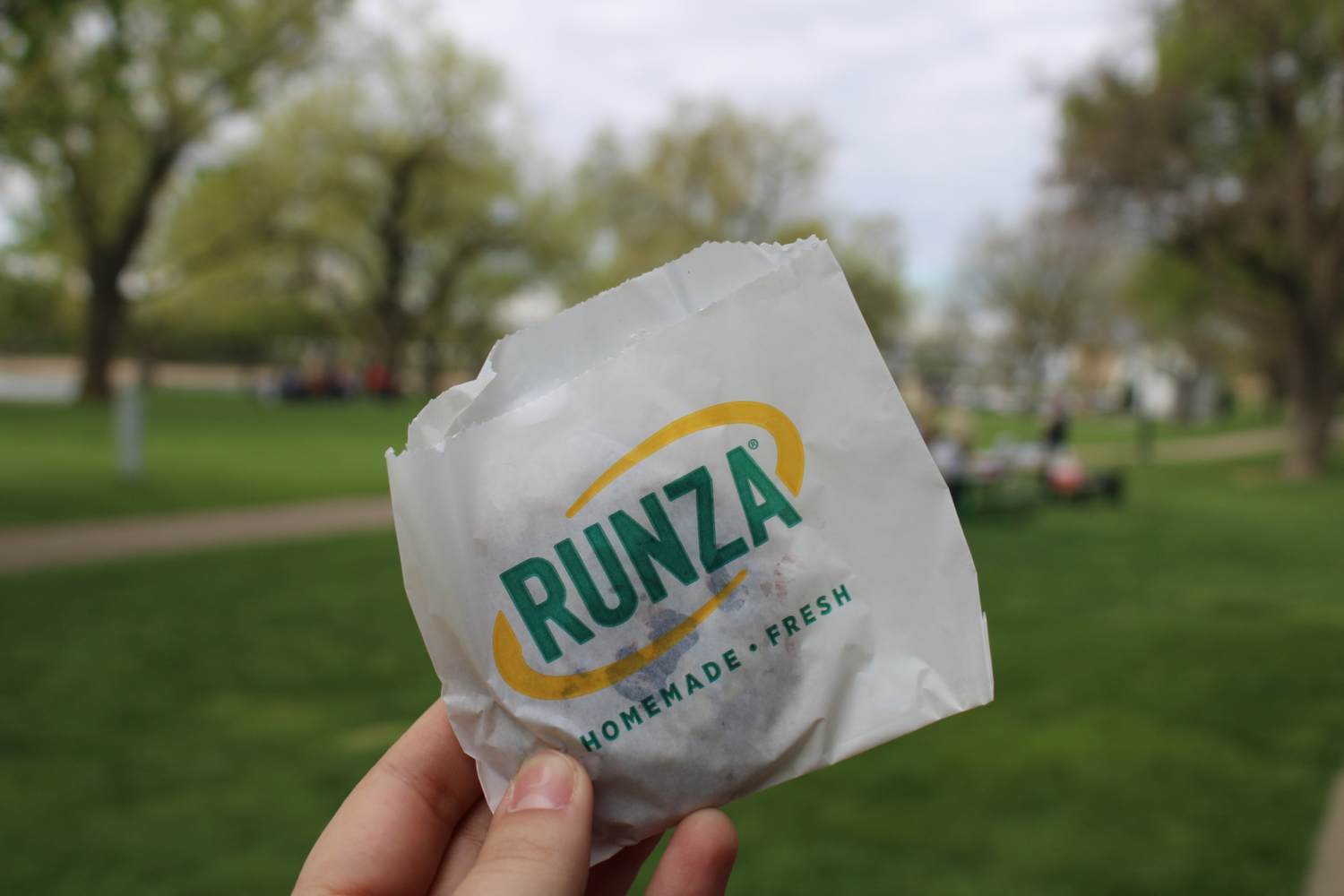A person holds up a cookie packaged in paper.