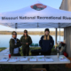 park rangers stand at a table with several clipboards laid out on it