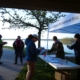 a group of people fill out a form on a clipbaord in front of a registration station