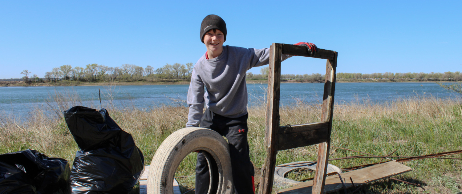A young boy poses with a tire and wooden structure