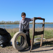 A young boy poses with a tire and wooden structure