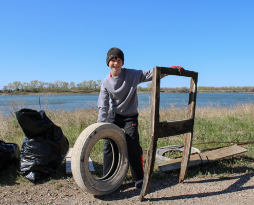 A young boy poses with a tire and wooden structure