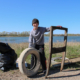 A young boy poses with a tire and wooden structure